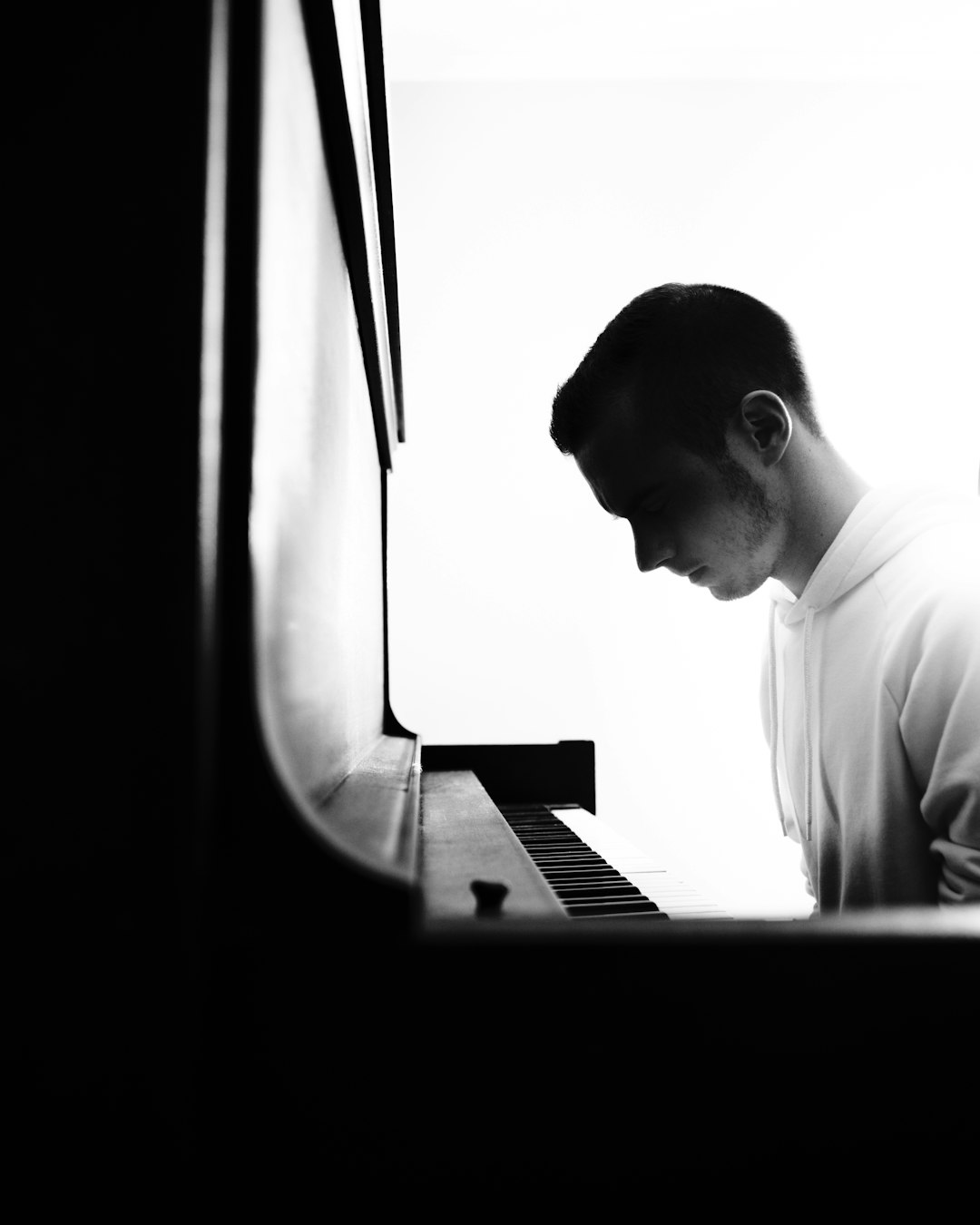 why-choose-us a-man-standing-next-to-a-piano-in-a-dark-room-ptcoltbwvoe