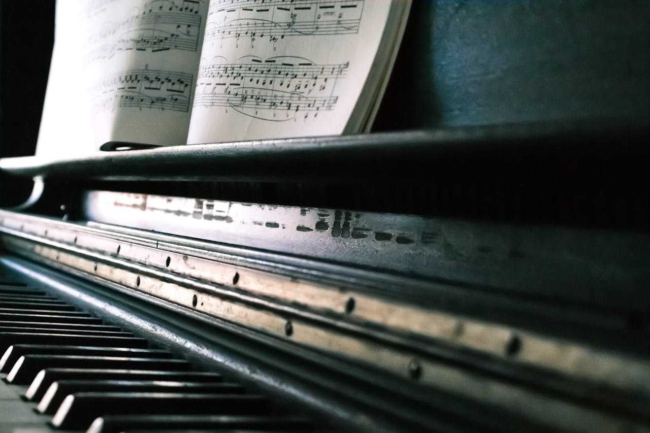hero-img-01 Close-up of piano keys with an open sheet music, creating a classic musical ambiance.