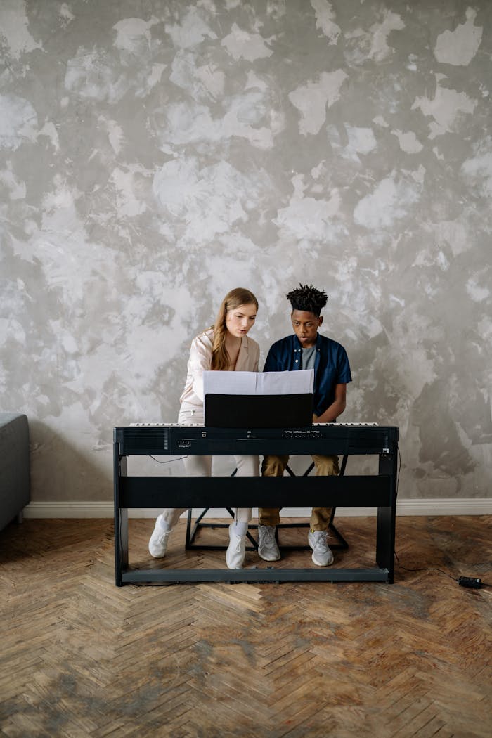 gallery-5 A young boy receives a piano lesson at home from a female instructor, focused and engaged.